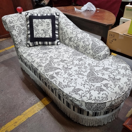 689 - A lavish chaise longue upholstered in complementary black and white floral and striped fabrics, with... 