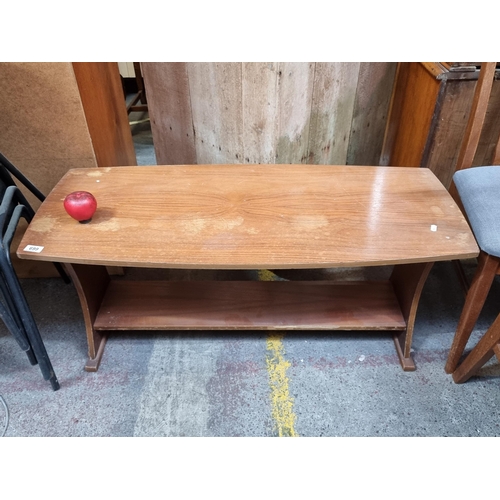 699 - A sleek vintage mid century coffee teak table with magazine shelf to base and lovely curved sides.