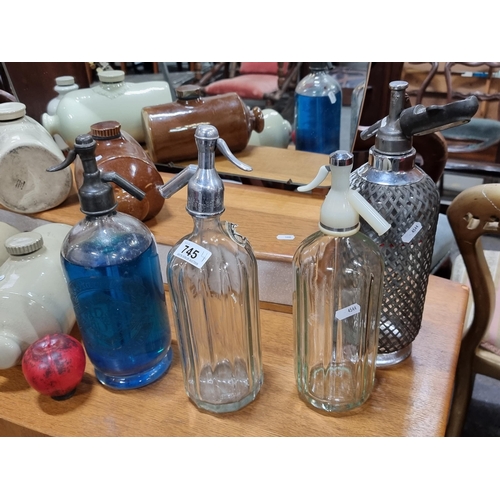 745 - Four vintage soda syphons in a variety of styles and sizes, each with a different faucet.