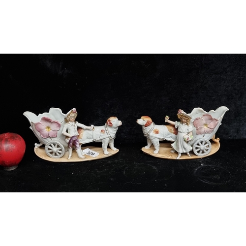 329 - A lovely pair of Capodimonte style porcelain figures featuring small figures with hound drawn carts,... 