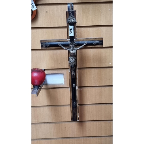 345 - A vintage wall hanging crucifix crafted from cast metal, mounted on a wooden back.