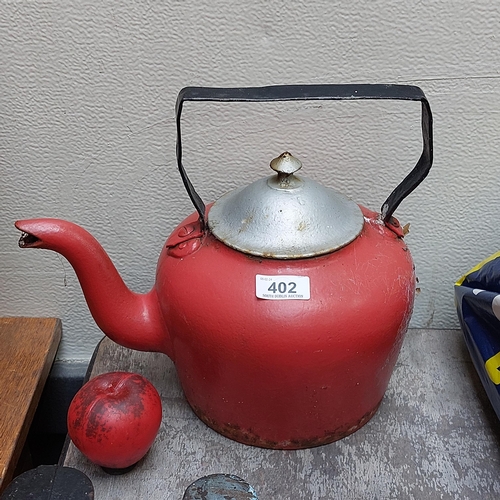 402 - A very heavy and large vintage cast iron kettle in a bright red enameled finish.