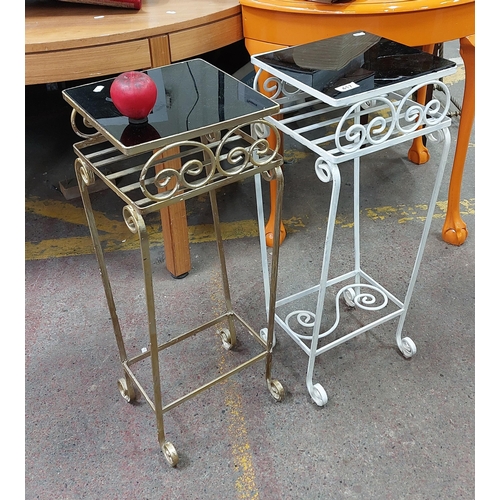 417 - A pair of cast iron ornate plant stands with black glass tops, one finished in a gold tone.