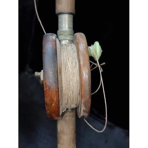 383 - A lovely vintage fishing pole with cork handle and wooden reel. In a dark green finish.