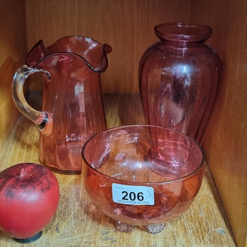 206 - Three beautiful pieces of cranberry glass including a footed bowl, a water jug with scalloped rim an... 