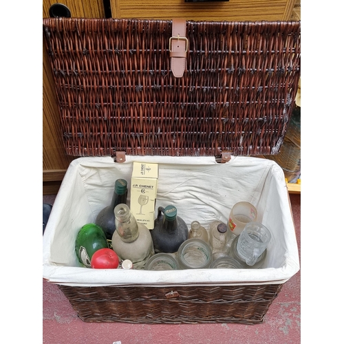 400 - A large wicker basket containing 16 vintage glasses and bottles. Including beer steins, a courvoisue... 