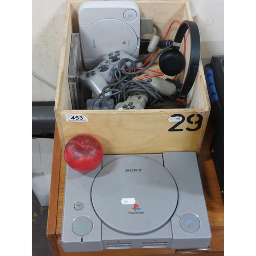 453 - A box containing two PlayStation 1 consoles, controllers, headset and cables.