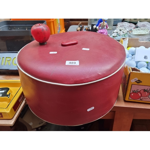 489 - A stylish mid century footstool upholstered in red leather fabric with white piping.