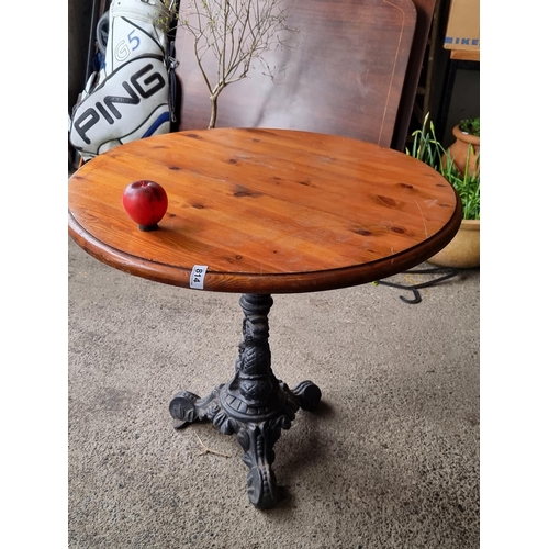 814 - A charming round cafe table with wooden top, held on a heavy cast metal base boasting fabulous dolph... 