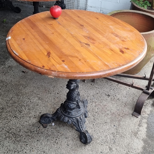 816 - A charming round cafe table with wooden top, held on a heavy cast metal base boasting fabulous dolph... 