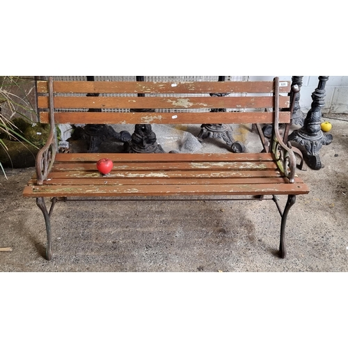 820 - A charming garden bench with slatted back and seat, held in wrought iron sides boasting scroll desig... 