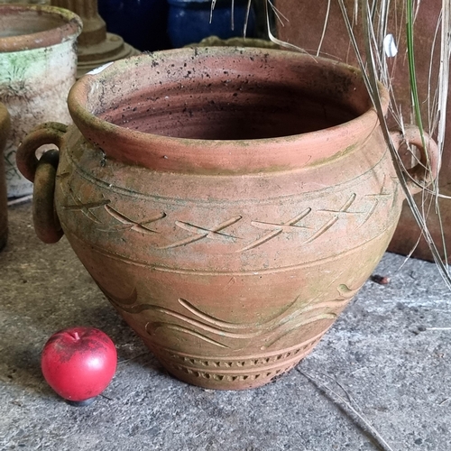 824 - An elegant and large terracotta garden planter in the form of a Grecian urn with handles to sides an... 