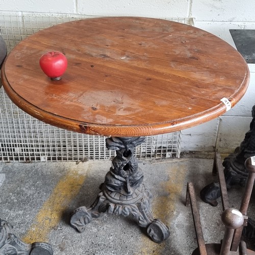 817 - A charming round cafe table with wooden top, held on a heavy cast metal base boasting fabulous dolph... 