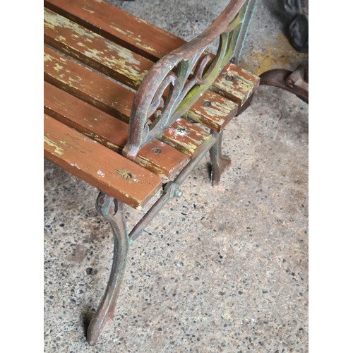 820 - A charming garden bench with slatted back and seat, held in wrought iron sides boasting scroll desig... 