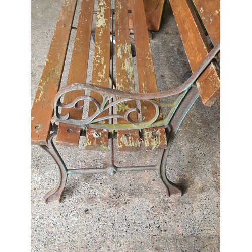 820 - A charming garden bench with slatted back and seat, held in wrought iron sides boasting scroll desig... 