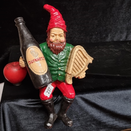 237 - A characterful Guinness advertising figure of a gnome cradling a large bottle of stout and a harp.