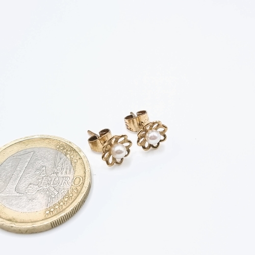 508 - A pair of nine carat gold pearl stud earrings set with floral mounts and butterfly backs.