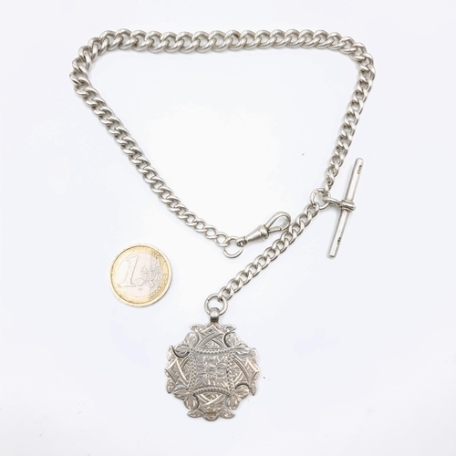 588 - An Edwardian sterling silver Albert chain with a finely decorated medallion plank to reverse. Hallma... 