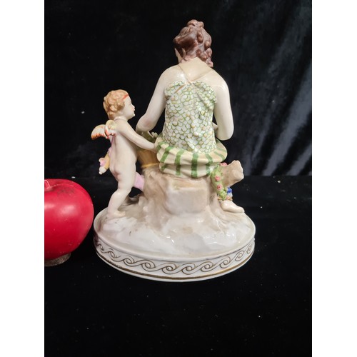 251 - A stunning Masons ceramic figurine depicting a woman making a flower crown with a cherub beside her.