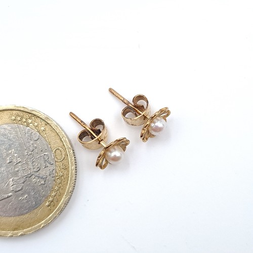 508 - A pair of nine carat gold pearl stud earrings set with floral mounts and butterfly backs.