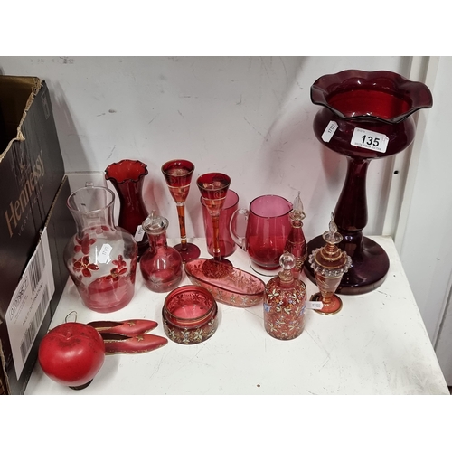 135 - A super lot of cranberry glass including handblown Egyptian perfume bottles with 24 carat gold detai... 