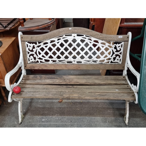 1019 - Star Lot : An Antique ornate cast iron and wood garden bench, boasting a decorative lattice and scro... 