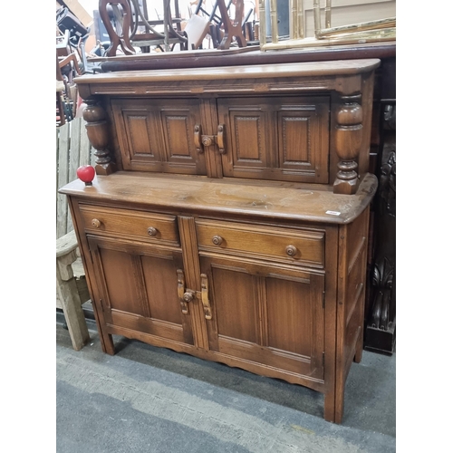 1020 - Robust oak sideboard, featuring classic paneled doors and robust turned columns—exuding a rich, hist... 