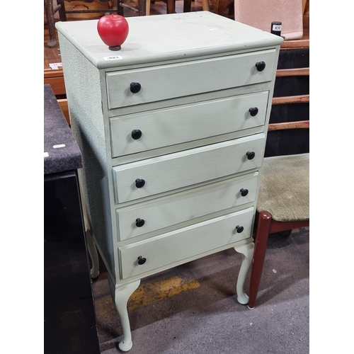 1023 - Charming, vintage chest of drawers with pastel finish and classic black knobs, exhibiting a time-hon... 