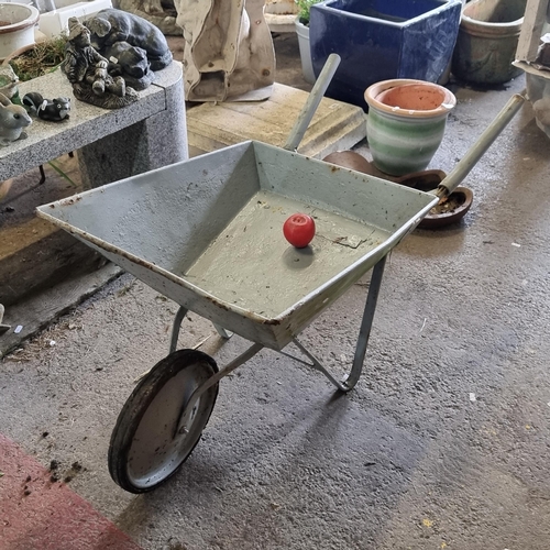 950 - A vintage wheelbarrow in a grey painted surface, ideal for rustic decor or garden display.