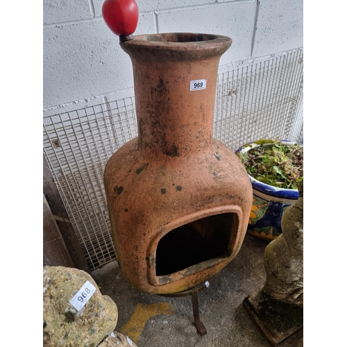 969 - A smart terracotta chiminea held on a cast metal tripod base, perfect for outdoor spaces.