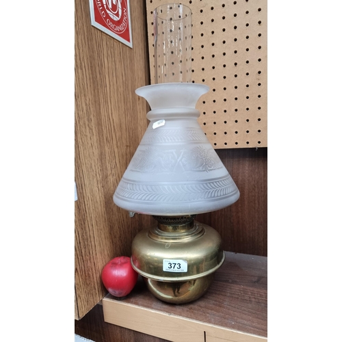 373 - As vintage oil lamp, with milk glass shade and glass chimney boasting elegant etched designs, with a... 