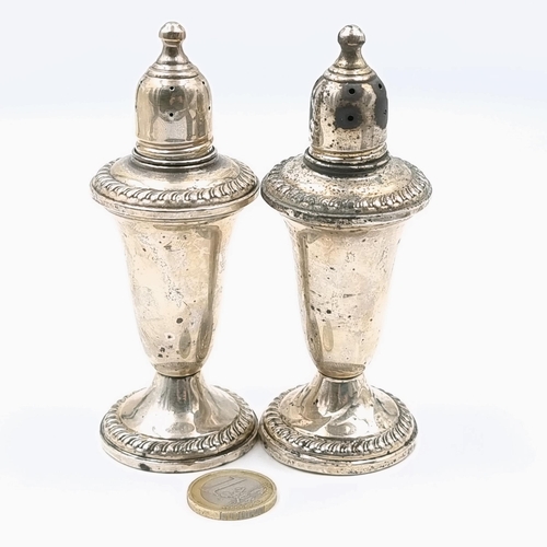 78 - A pair of sterling silver pepperettes with finial tops. Set with pie crust detailing to rim and base... 