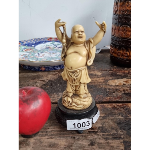 1003 - A harmonious carved buddha figurine, jovial expression, held on a wooden pedestal, an evocative coll... 