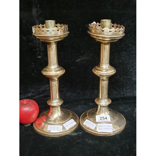 254 - A pair of antique polished brass ecclesiastical candle sticks with castle turret wax catchers.