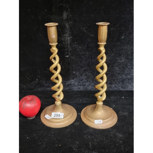 299 - A pair of vintage tall brass candle sticks featuring a barley twist design.