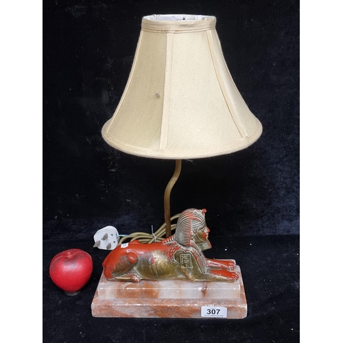 307 - A lovely vintage Egyptian table lamp in the form of a sphynx, resting on a red and white stepped mar... 