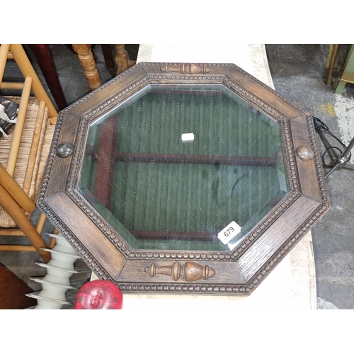 679 - A beautiful arts and crafts  carved octagonal bevelled wall mirror, featuring robust detailing and e... 