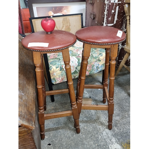 684 - A pair of classic sleek vintage mahogany bar stools with leather upholstery, four turned legs to eac... 