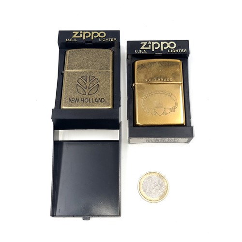 565 - Two boxed unused Zippo lighters. One in antique brass together with a solid brass Irish Claddagh exa... 