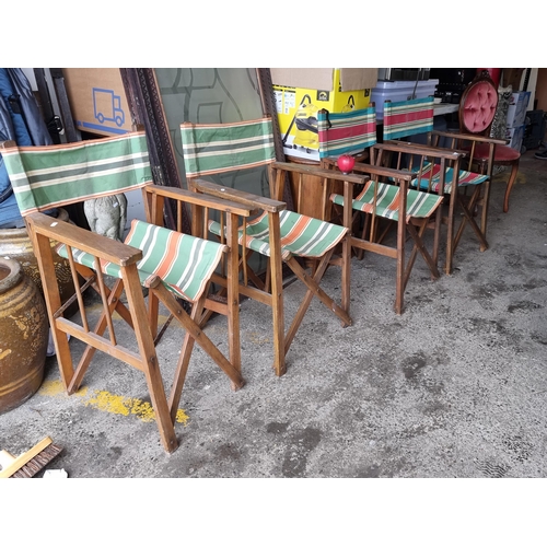 927 - A Set of four vintage wooden folding 
director's chairs with striped canvas, exuding a nostalgic cha... 