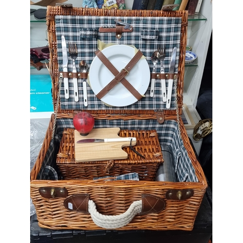 828 - A large wicker picnic basket with leather clasps and handle, containing champagne flutes, mugs, a th... 