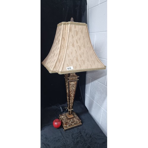 812 - An elegant tall table lamp boasting a gilt stem embellished in Neoclassical motifs, topped with a fa... 