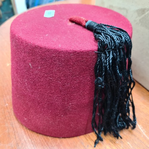 852 - A red vintage hat box with a vintage red fez hat etc.