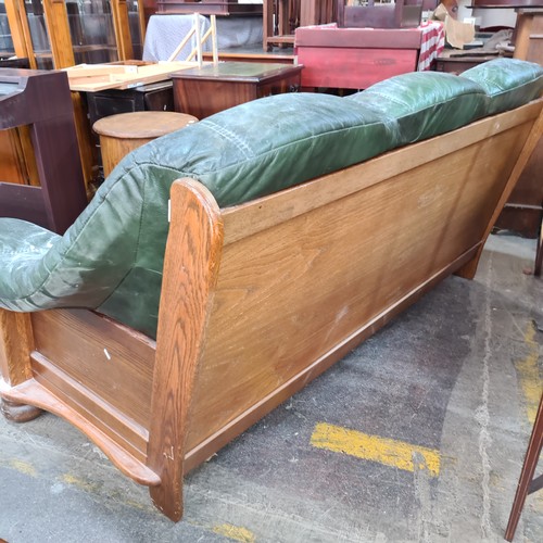 1112 - A fabulous oak three seater vintage sofa complete with green leather seating. Features a bun feet an... 