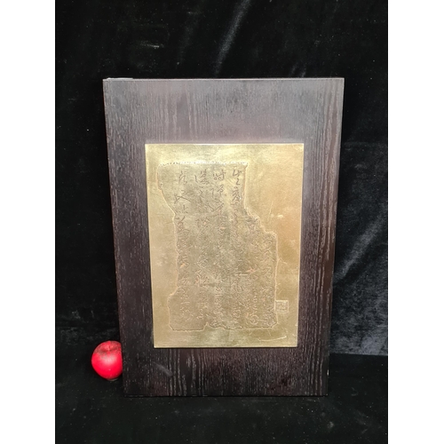 65 - A gilt touched cast metal with Japanese engraving. Mounted on solid wood board.