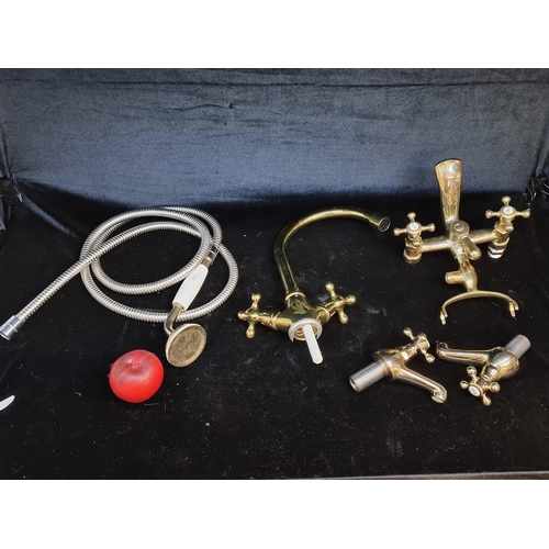 214 - A box containing multiple antique  brass taps, kitchen mixer taps, bath taps a and shower head.