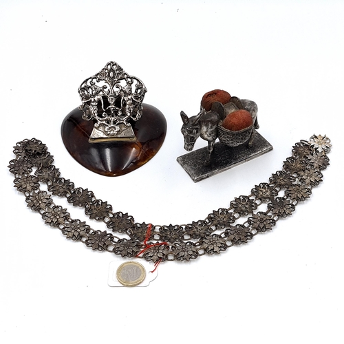 Three interesting antique items consisting of a silver letter paper clip with cherub detailing mounted on a faux tortoise shell base. Together with a floral panel belt (Length - 85 cms) and an interesting pin cushion depicting a donkey carrying basket satchels.