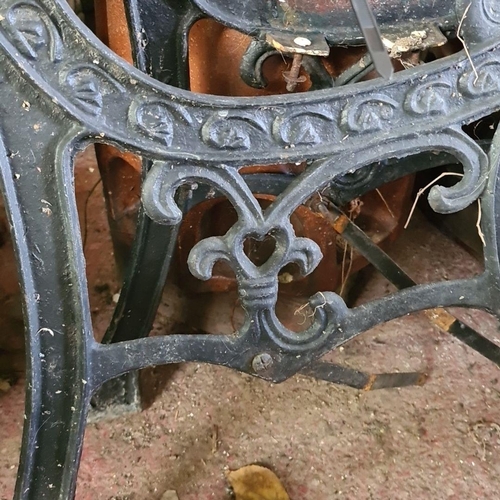 869 - A decorative cast iron garden bench frames with intricate scrollwork and heart motif.