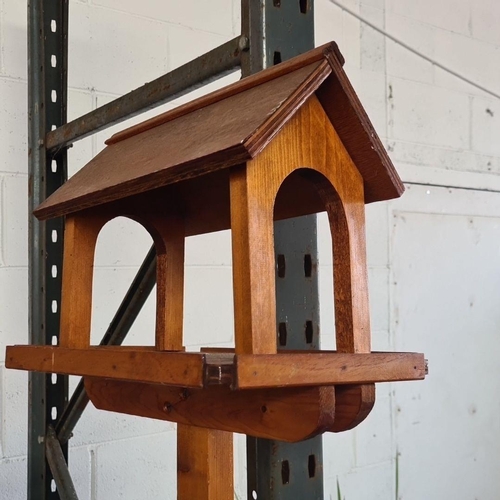 871 - A hand-crafted wooden bird feeder in warm toned wood finish. Approx 7 feet tall.