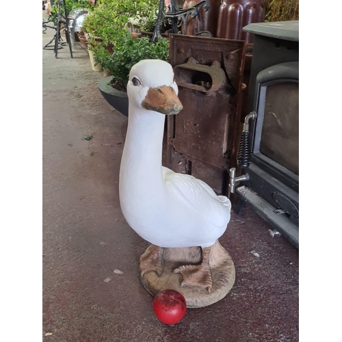 873 - A decorative large stone wooden goose statue, perched atop a naturalistic base.